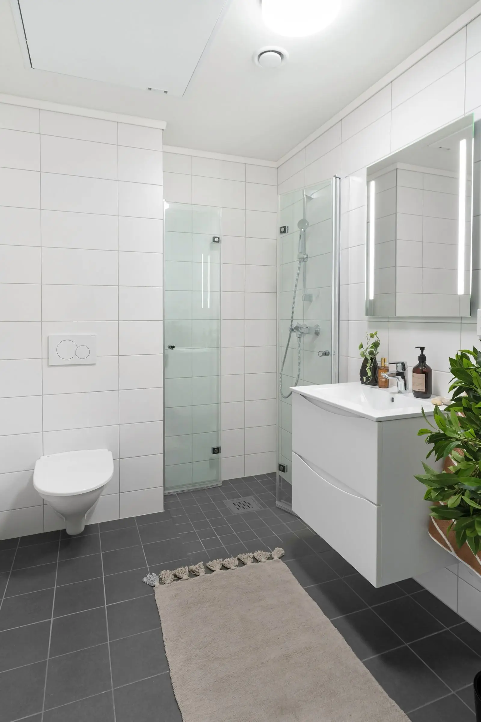 Baño remodelado con enchape blanco, piso gris y mueble flotante